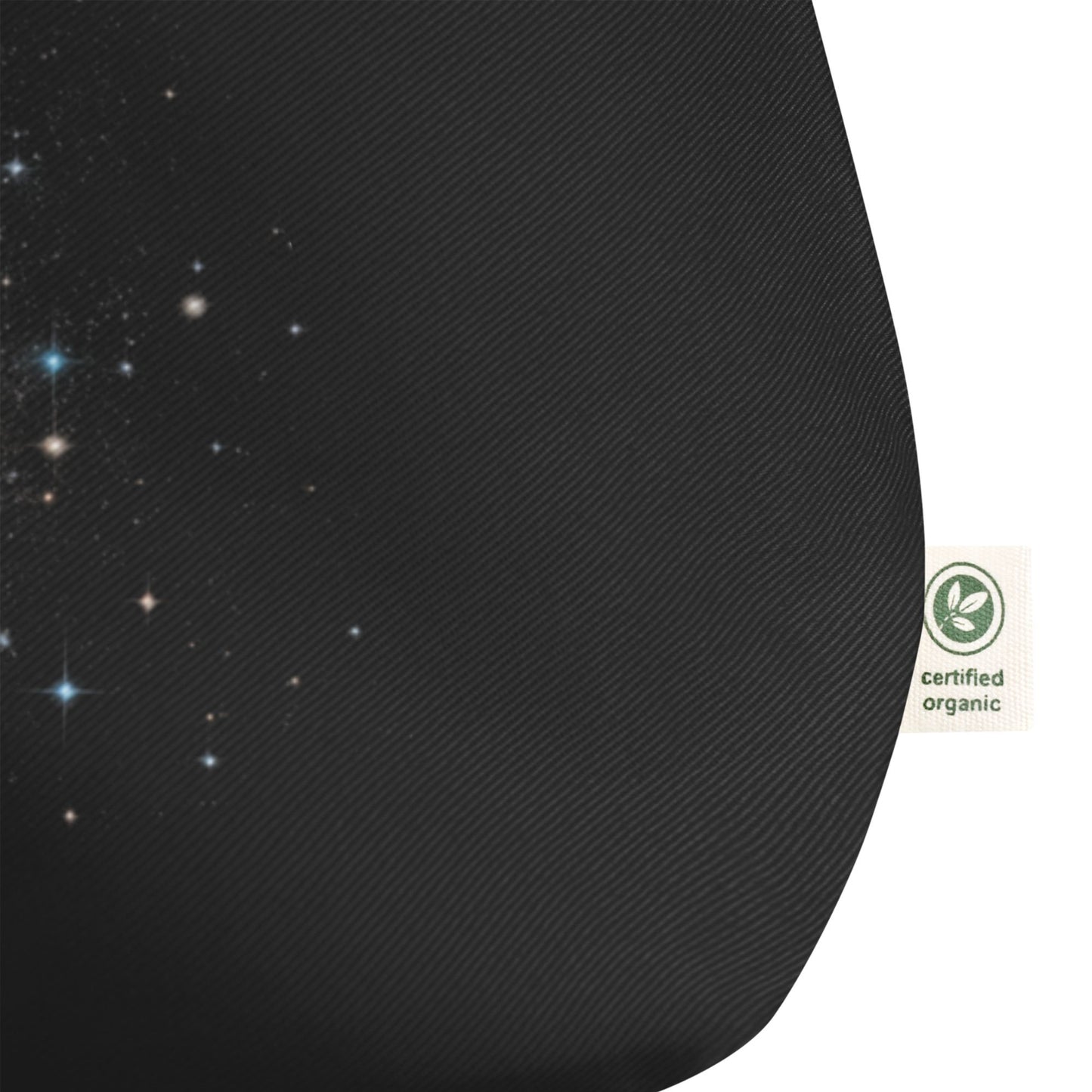 Close-up of a black tote bag with a starry sky design and a certified organic label on a transparent background