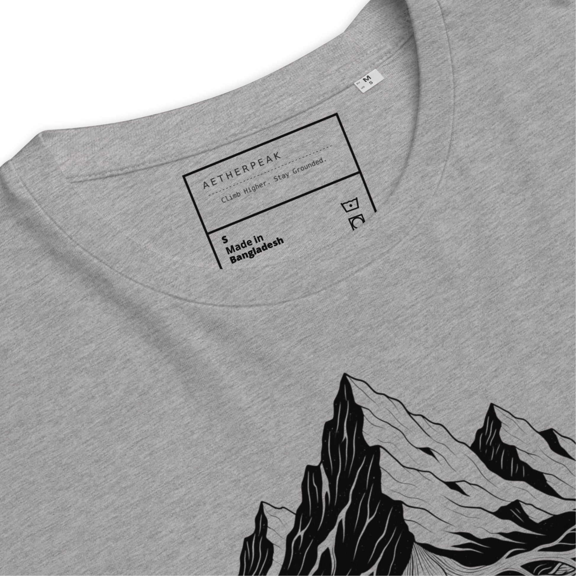 Close-up of Aether Peak Roots tee in grey, showing the neck label and black mountain graphic print.
