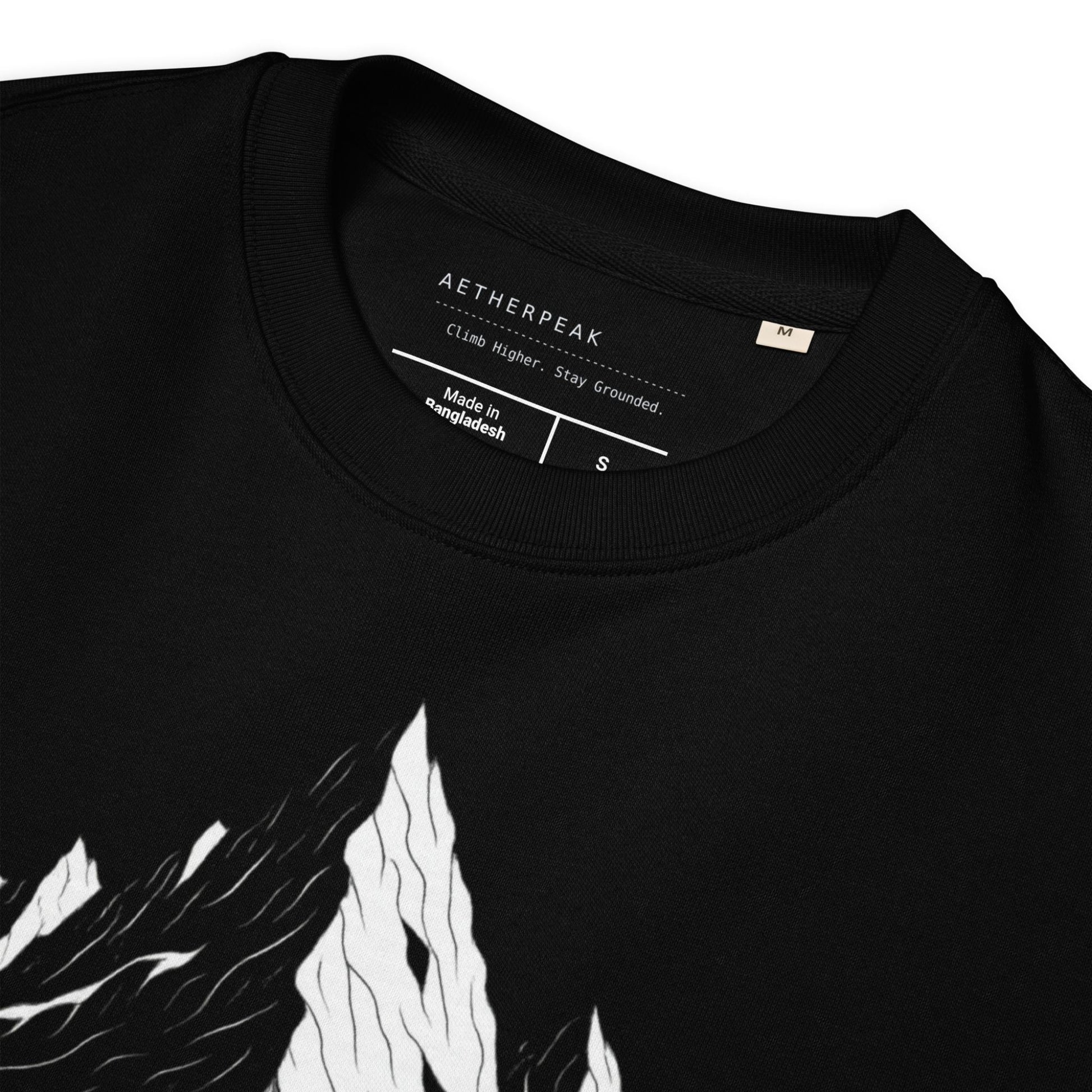 Close up of black sweatshirt with white mountain design and 'Aetherpeak' label on a white background