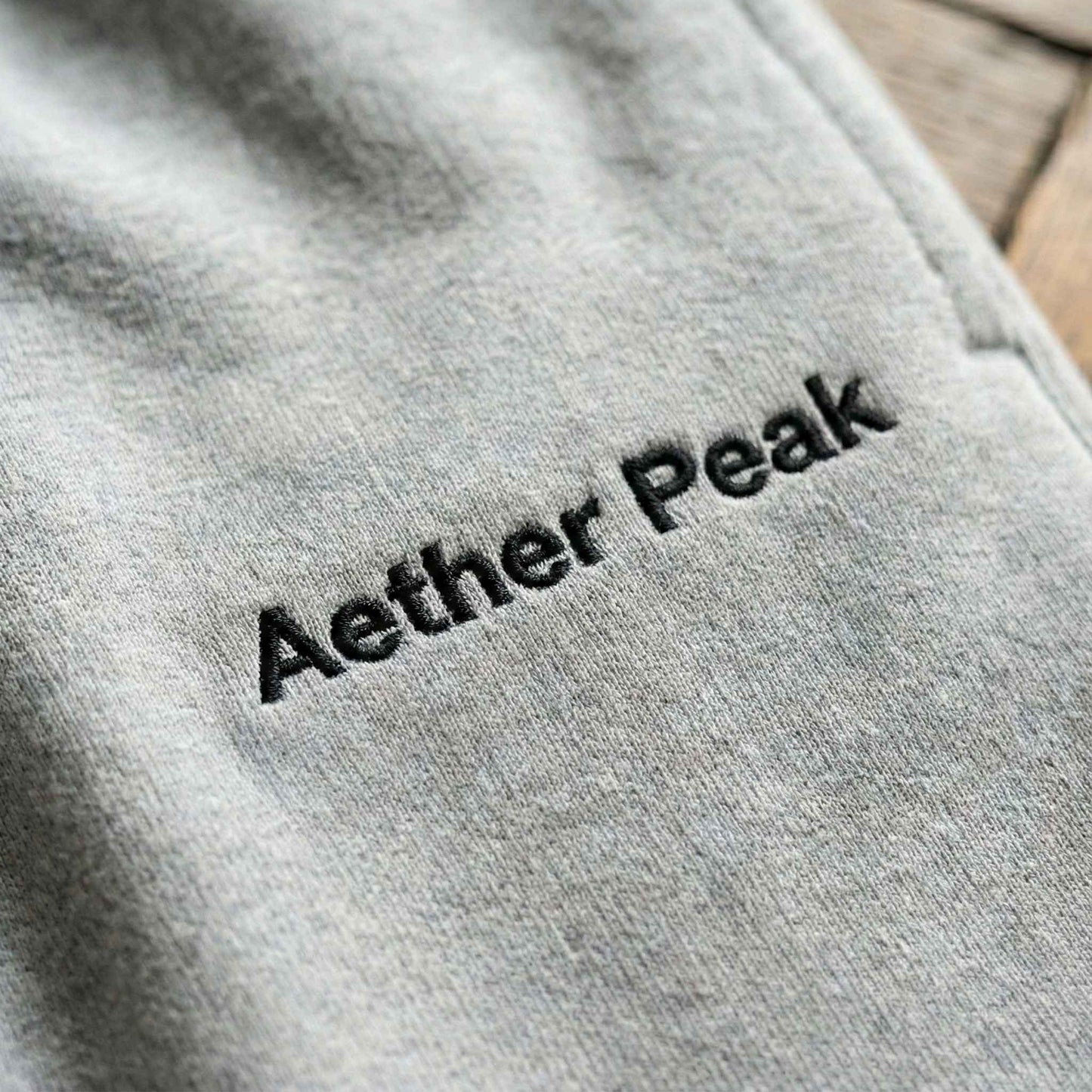Heather Grey joggers with 'Aether Peak' embroidered on them.