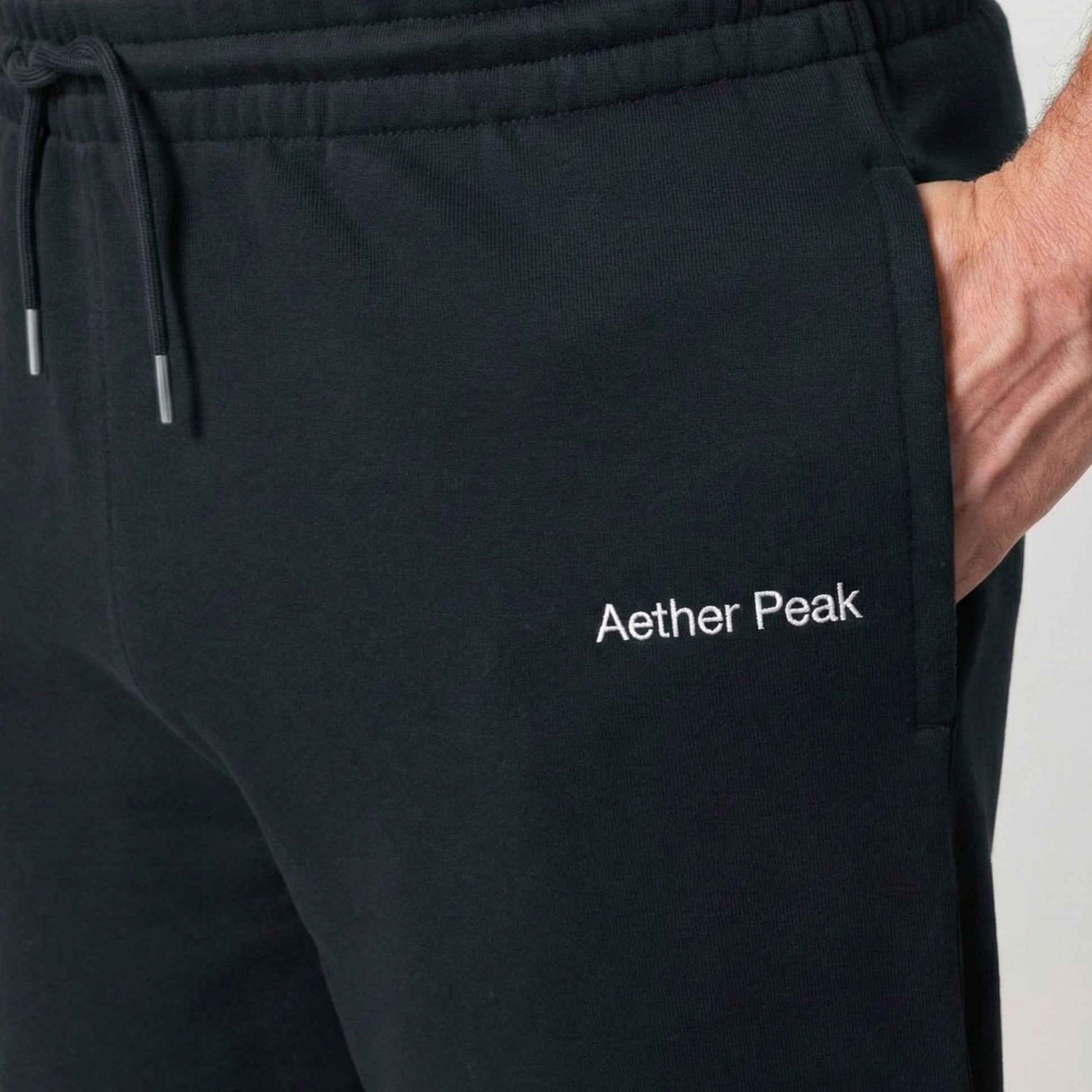 Close-up of the Aether Peak black joggers logo and front pocket.