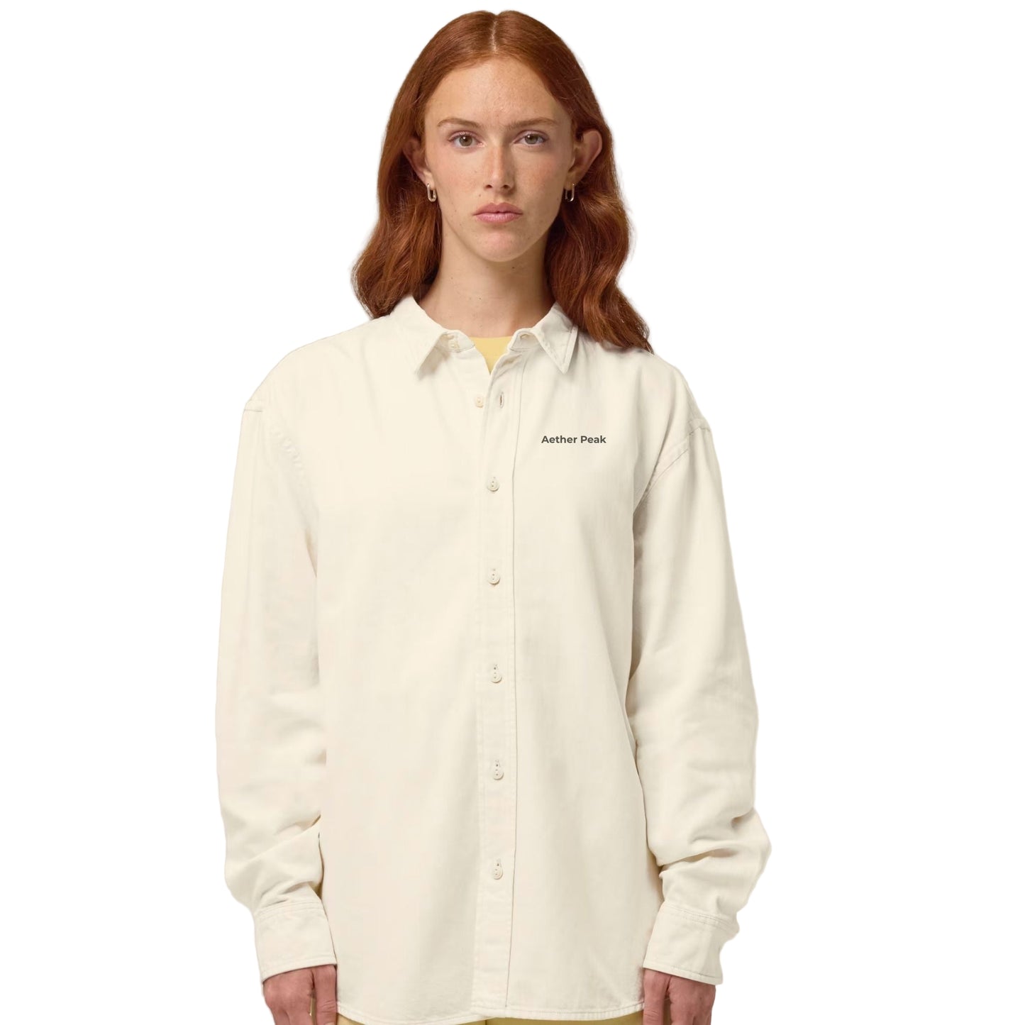 A woman  wearing the Desert Dust organic cotton  overshirt with the Aether Peak logo on a white background