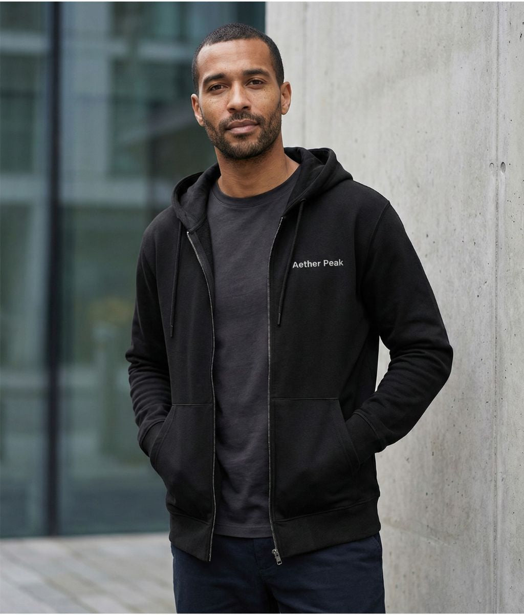 A man wearing the Aether Peak black organic cotton zipped hoodie outdoors.