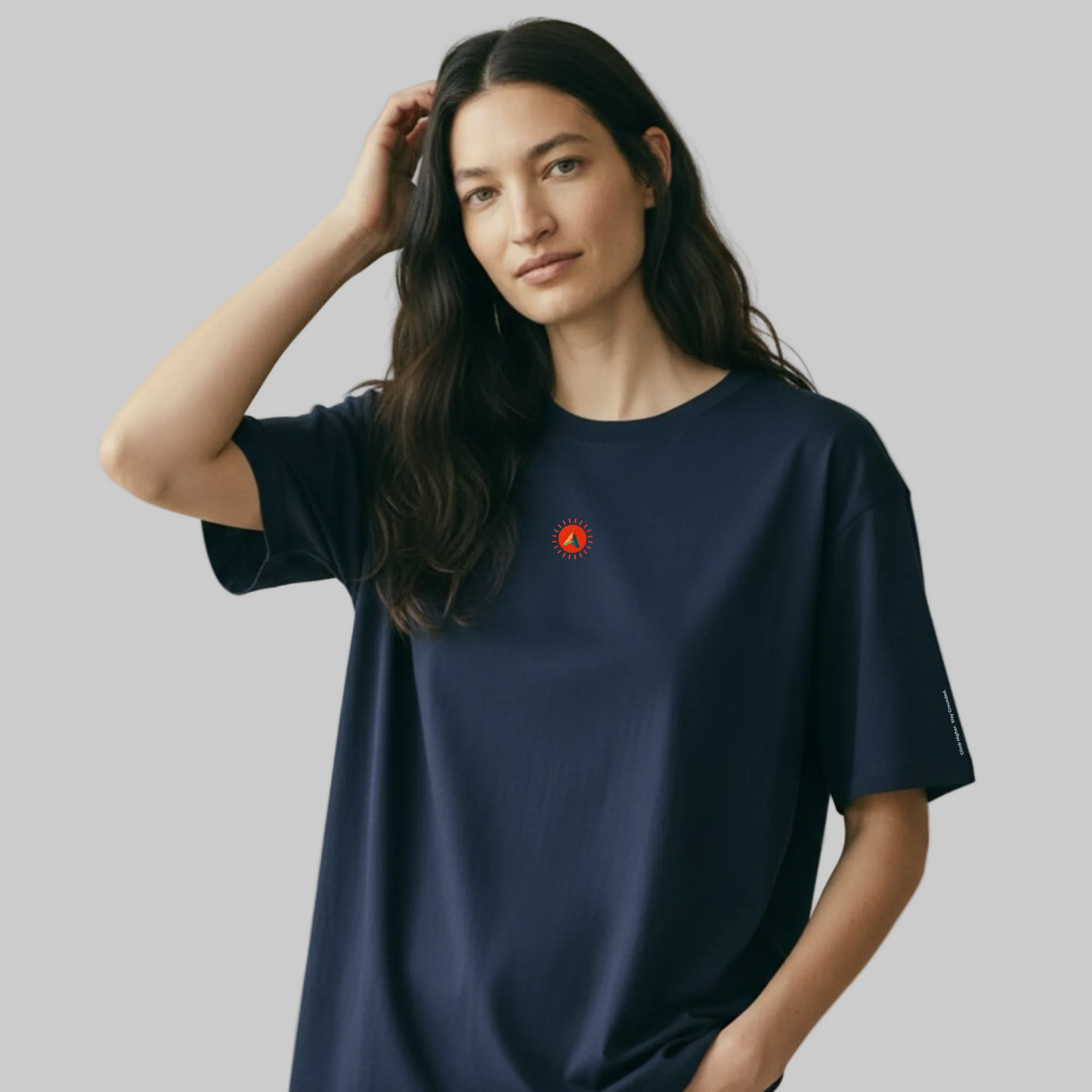 Female model wearing the Aether Peak French Navy organic cotton oversized t-shirt with a small Sunburst print on a white background.