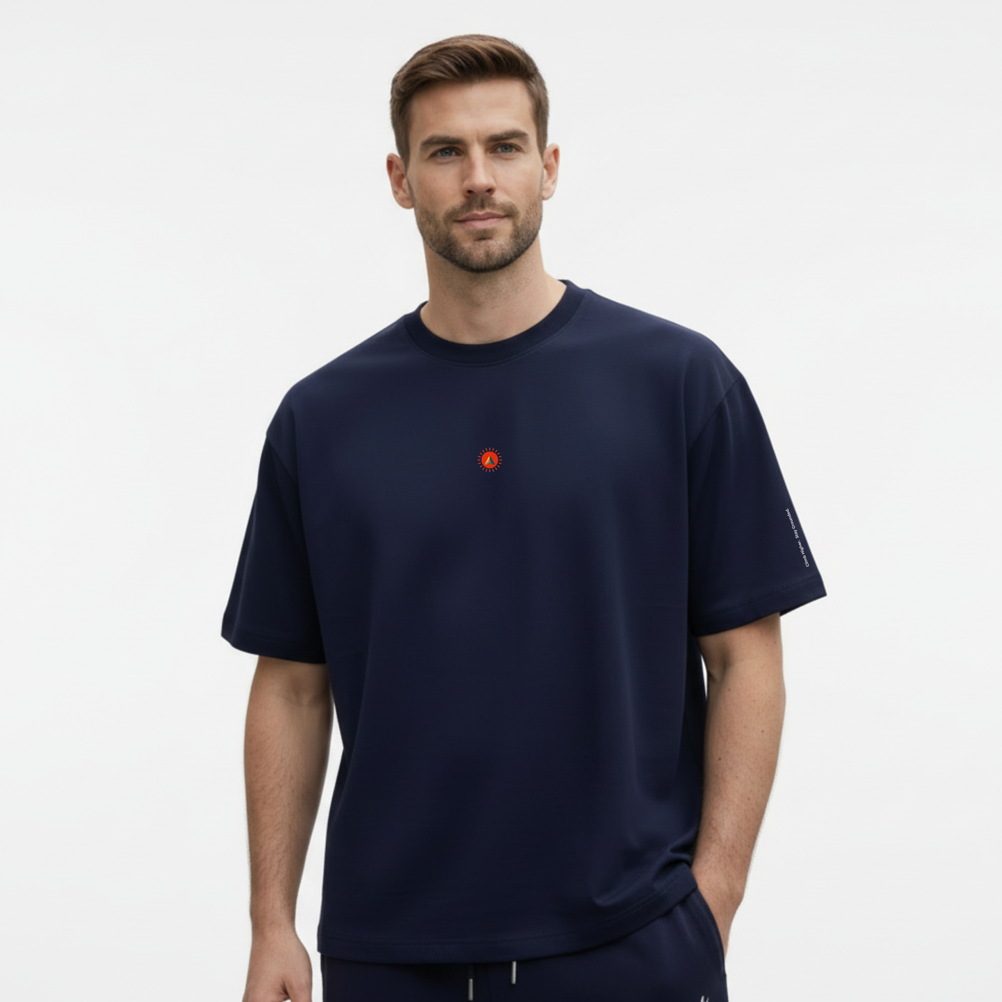 A male model wearing the French Navy organic cotton oversized t-shirt with a sunburst logo on the chest against a white background.